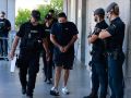 Declaran los detenidos por la redada frente a pancartas de “policía asesino” Agentes de la Policía Nacional conducen a uno de los detenidos, este jueves