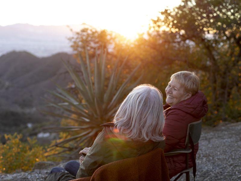 Dos mujeres mayores en una escapada la naturaleza sentadas en sillas y disfrutando de su tiempo