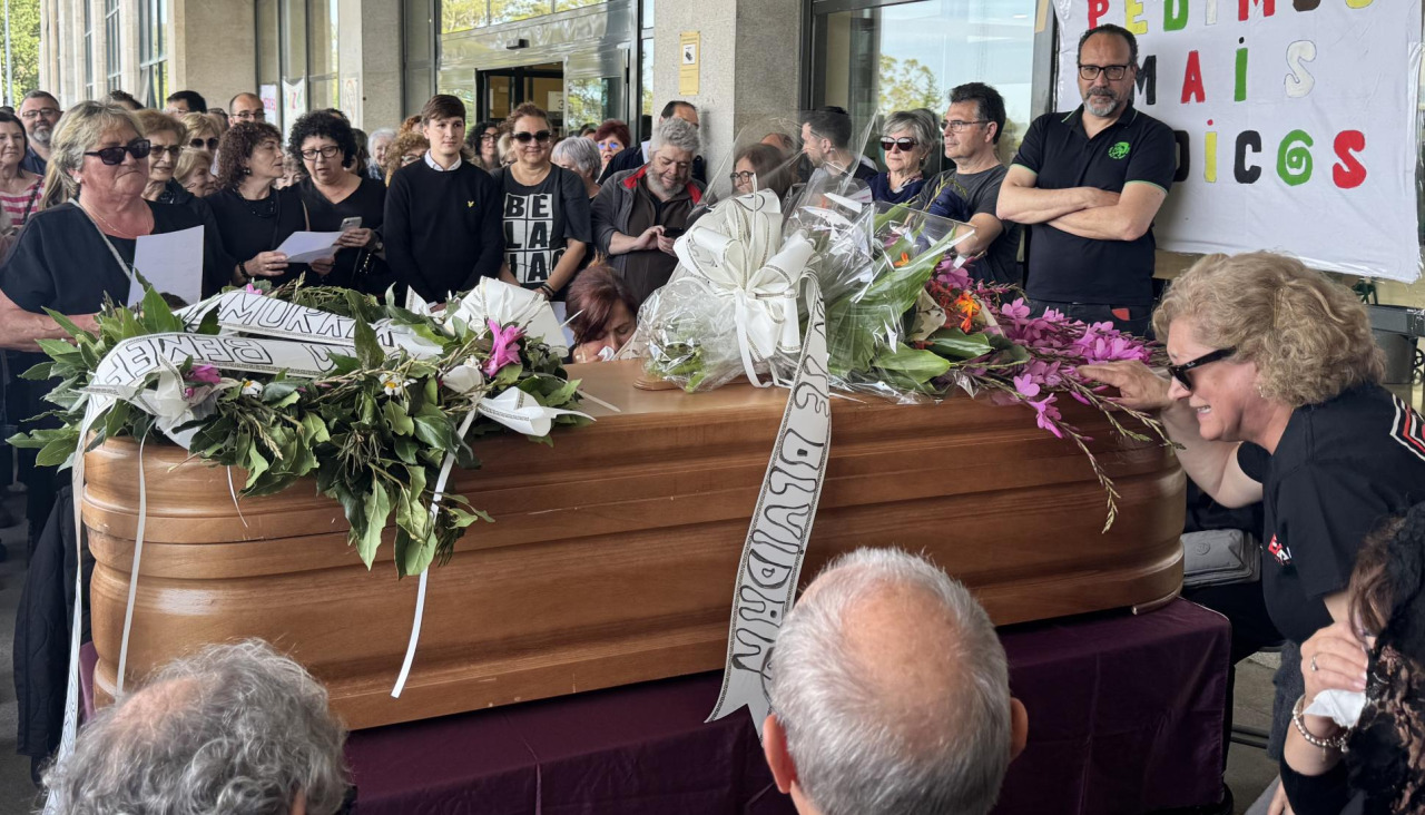 Una mujer se acerca al ataúd, ante el que llora, para expresa su pesar por la "morte da Sanidade Pública"