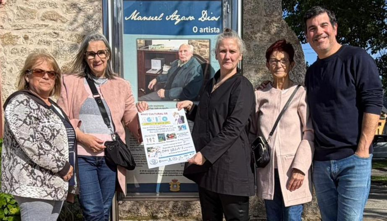 Josefa Suárez, Pilar Millet, Elvira Pisos, Rosa Millet e Unai González, directivos da asociación Francisco Lorenzo Mariño, muestran el cartel de actividades delante del panel de Manuel Ayaso en la casa de cultura que lleva su nombre
