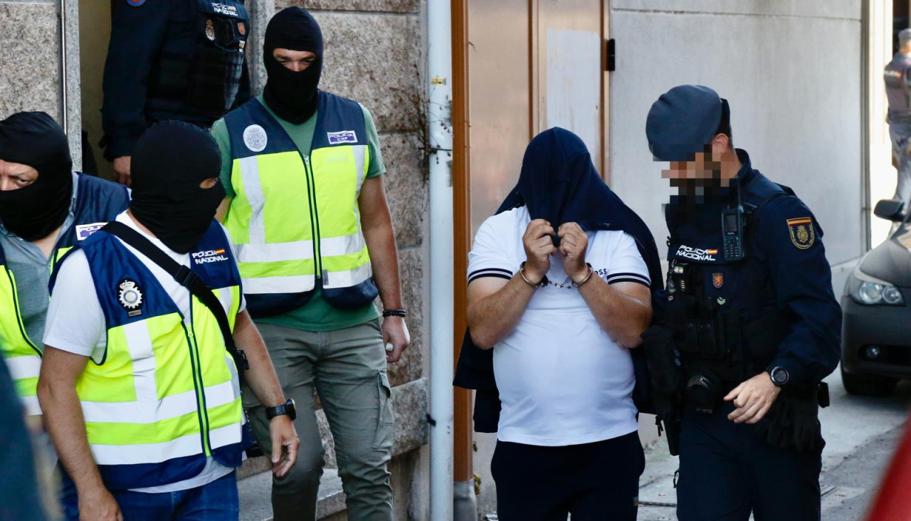 Varios agentes custodian a uno de los arrestados esta mañana, en uno de los registros, en la vilanovesa zona de O Cabo