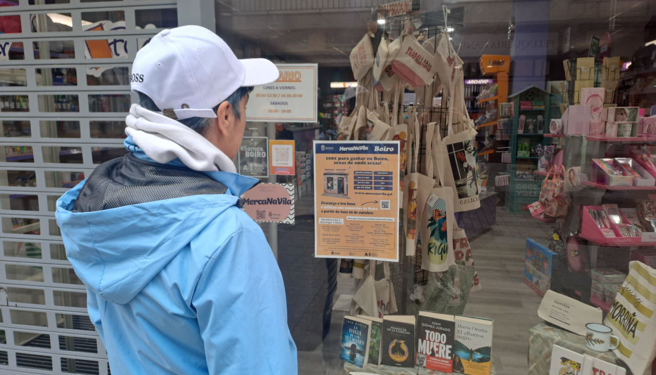Un viandante se detuvo a ver el cartel de la campaña ‘Mercanavila’ que exhibe un establecimiento de Boiro