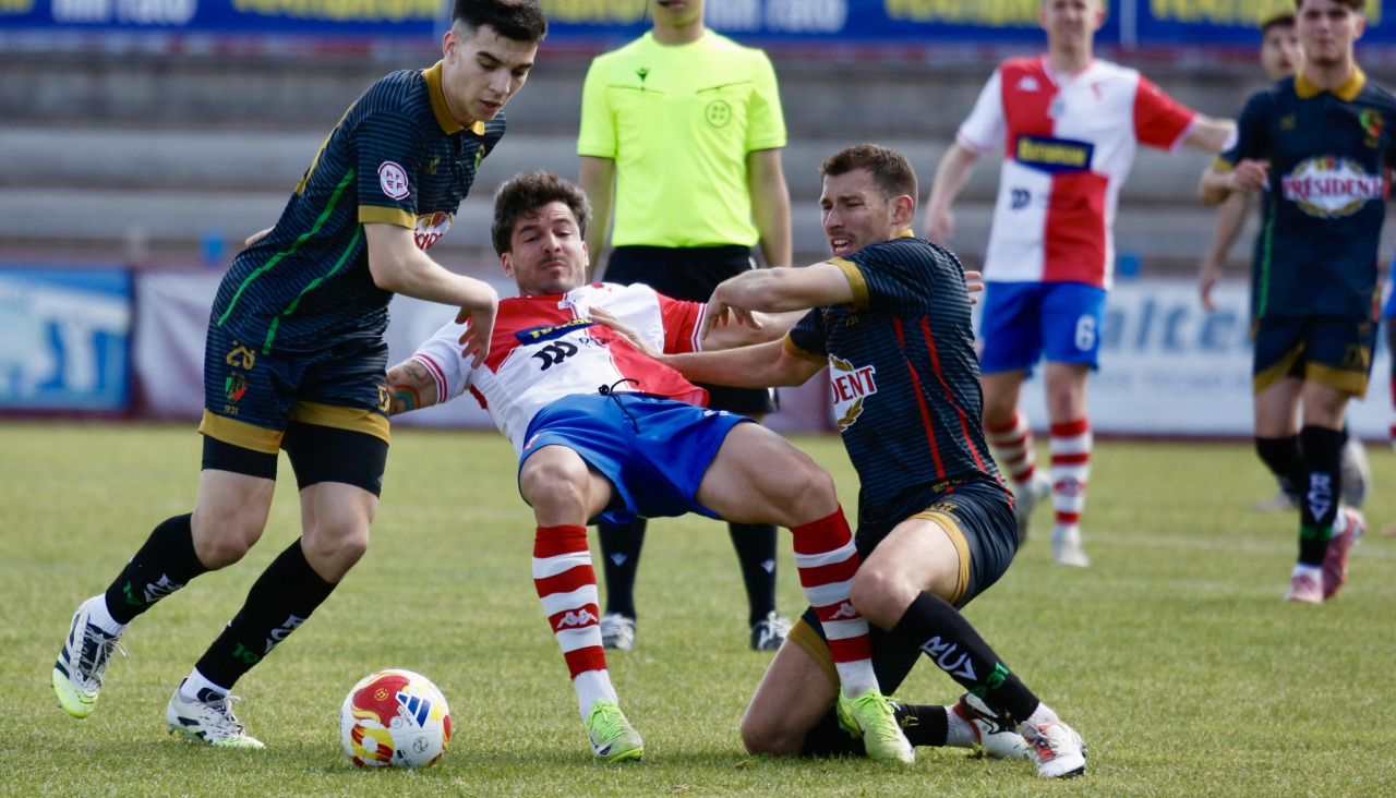 Dos jugadores del Vilalbés impiden el avance del goleador Álex Rey