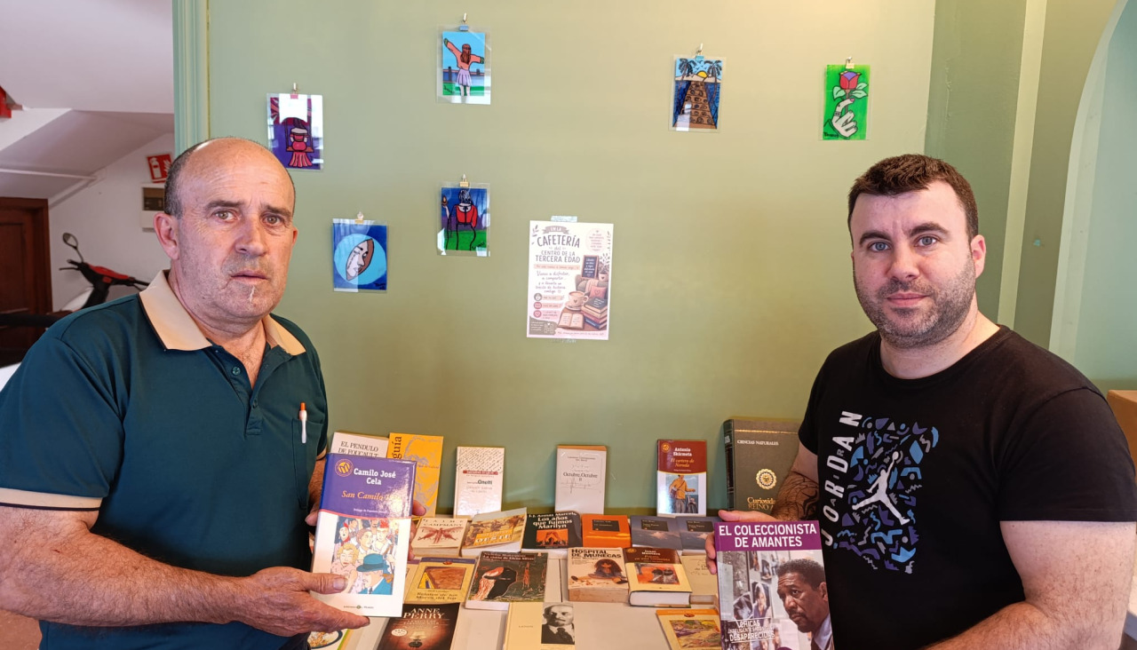 Tono Caneda y Adán Caneda, posan con los libros que regalan en su cafetería de O Grove