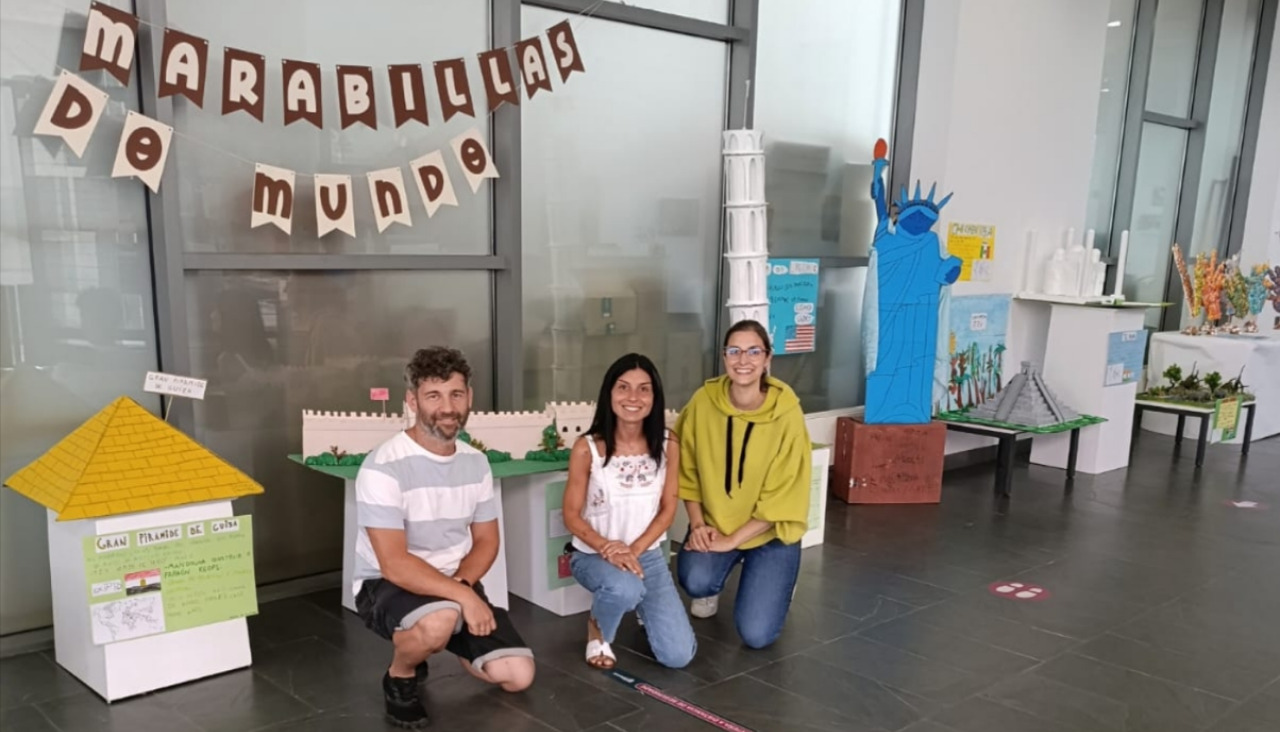 José Bastos, profesor de Educación Física, Paula Deira, directora del CRA de Rianxo, y María Varela, maestra de Música,, posan junto a la exposición de maquetas en el auditorio municipal