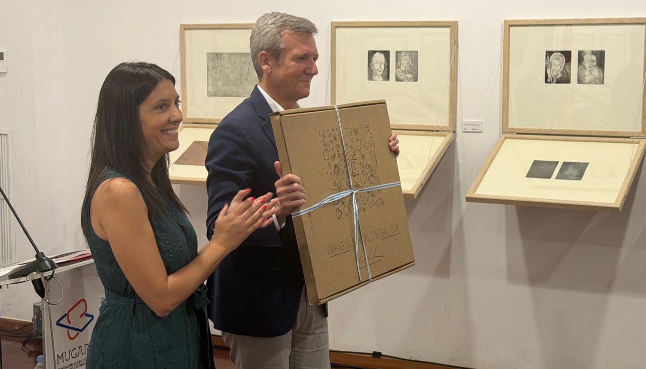 La presidenta de la Fundación Museo de Artes do Gravado á Estampa Dixital, María Sampedro, le entregó una carpeta con la obra expuesta de Xaime Quessada en el Mugart al presidente de la Xunta de Galicia, Alfonso Rueda